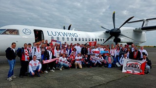 Fußballfan-Gruppenfoto vor einer Propellermaschine