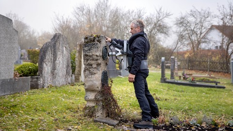 Grabsteinprüfer bei der Arbeit auf dem Friedhof