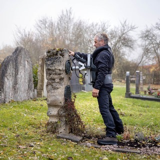 Grabsteinprüfer bei der Arbeit auf dem Friedhof