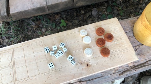 Holzbrett mit Spielsteinen und Würfeln