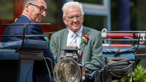 Cem Özdemir in Bad Urach beim 300 Jahre Jubiläum Schäferlauf. Er sitzt gegenüber von Ministerpräsident Kretschmann und schaut in die Menschenmenge.