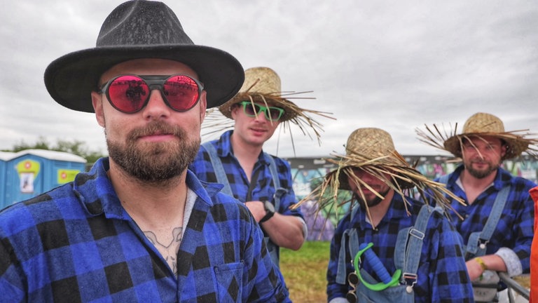 Eine Fangruppe mit gleichfarbigen Hemden und Hüten auf dem Kopf beim Southside-Festival 2024 in Neuhausen ob Eck. Die Jungs wollen sich dem Regen stellen.