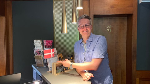 Steffen Schillinger, der Hotelbesitzer, zeigt auf eine kleine dänische Flagge an der Hotelrezeption