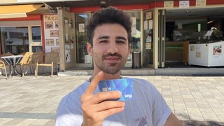 Mohamad Sami Dabbas hält seine Bezahlkarte in die Kamera. Der Asylbewerber ist vom System mit der Karte genervt.