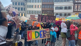 Auf dem Tübinger Marktplatz vor dem Rathaus halten Schüler, Lehrer und Eltern Plakate hoch. Sie protestieren gegen die Sparpläne der Stadtverwaltung, die auch die Schulen betreffen.