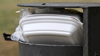 Ein voller Mülleimer mit Verpackungsmüll: Steuerberater eines Unternehmens machen aus Tübingens Verpackungssteuer ein Geschäft. Zumindest bieten sie ihre Hilfe an und schreiben an Städte.