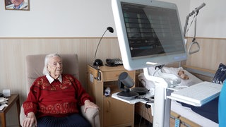 Die Patientin sitzt auf einem Sessel in ihrem Zimmer im Pflegeheim. Vor ihr steht der Medienturm, mit dem sie von der Ärztin telemedizinisch untersucht wird. Das Pilotprojekt HeimDoc ist ein Versuch der Reutlinger Kreiskliniken und der RAH, die hausärztliche Versorgung zu verbessern.