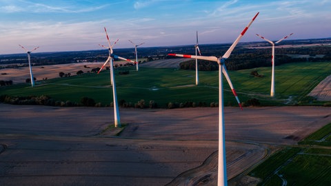 Die Abendsonne beleuchtet die Windkraftanlagen in einem Windpark. (Symbolbild)
