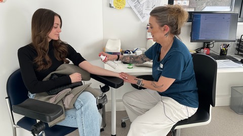 Eine Praxismitarbeiterin nimmt der Patientin Sarah Kiene Blut ab. Sie hat über ein Jahr lang einen Facharzt gesucht.