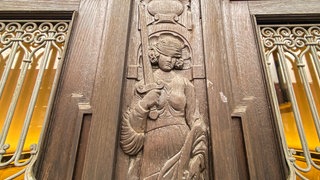 Geschnitzte Justitia an einem Türrahmen aus Holz im Landgericht Tübingen.