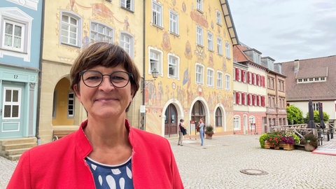 Saskia Esken (SPD) lächelt herausfordernd in die Kamera. Im Hintergrund das Rathaus von Horb mit seiner historischen Fassadenmalerei.