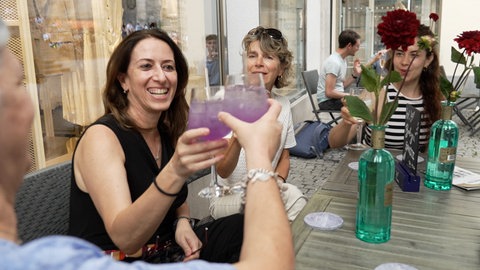 Vier Frauen stoßen vor einer Tübinger Bar mit Cocktails und alkoholfreien Drinks an.
