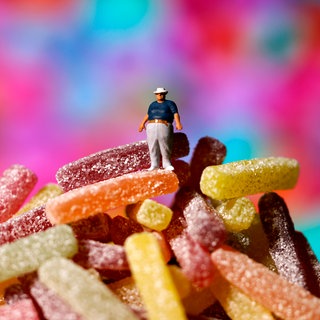 Ein Mann mit Adipositas steht auf einem Berg Süßigkeiten. 