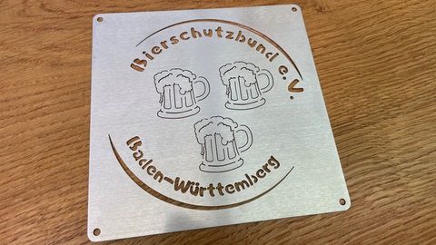 Eine Metallplatte mit dem ausgsschnittenen Logo des Bierschutzbund e. V. Baden-Württemberg. Am 27.03.25 wurde in Zwiefalten der Bierschutzbund gegründet.
