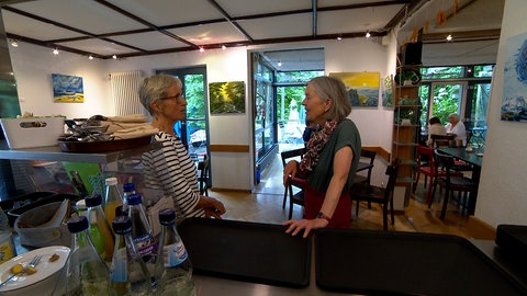 Barbara Haas und Christine Heppner im Gastraum vom Kaffeehäusle Reutlingen. Große helle Fenster lassen viel Licht herein. 