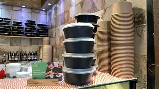 Mehrweggeschirr stapelt sich auf dem Tresen eines Imbisses in Tübingen zum Thema Verpackungssteuer