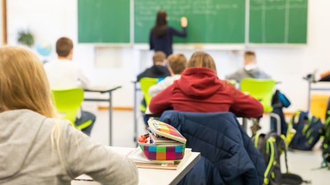Schüler sitzen an Tischen im Klassenraum