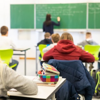 Schüler sitzen an Tischen im Klassenraum