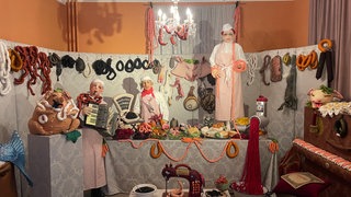 Fleisch, Wurst, Käse und Austern aus Stoff sind überall in der Auslage bei Familie Schweinesbein verteilt. Diese Szenerie der Künstlerin Alraune ist die erste in der Ausstellung in Beuron.