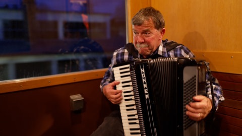 Ein Mann im Zug spielt Akkordeon. Er ist extra aus der Schweiz gekommen um bei der Trossinger Mondscheinfahrt dabei zu sein.