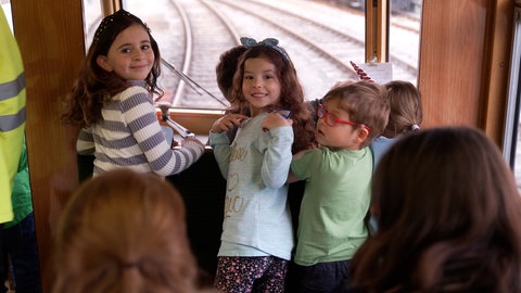 Kinder knien auf der Sitzbank direkt hinter dem Zugführer. Sie lächeln in die Kamera. Die Trossinger Museumsbahn macht sich auf den Weg: Mondscheinfahrt angesagt!