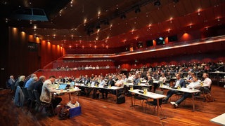 Die Kreisräte des Zollernalbkreises sitzen an Tischen in der Balinger Stadthalle. 
