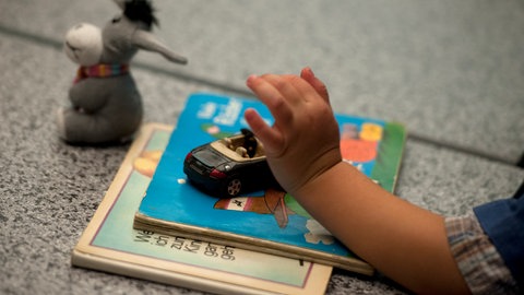 Symbolbild: Ein Pflegekind spielt während einer Pressekonferenz des Kinder- und Jugendhilfe-Verbundes.