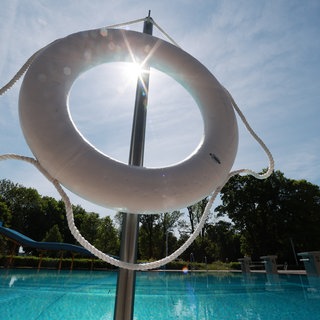Ein Rettungsring hängt in der Sonne in einem Freibad. (Symbolbild) Bei einem Badeunfall in einem Erlebnisbad in Albstadt (Zollernalbkreis) war ein Mädchen ertrunken.