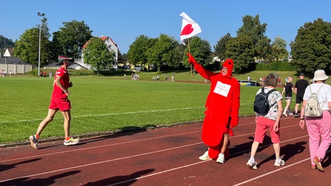 Ein Mann in einem Hummer-Kostüm hält eine weiße Fahne hoch. Beim Protestlauf in Münsingen wurde für die Notfallpraxis demonstriert.