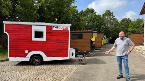 Tüftler Nico König steht vor fertig produzierten Tiny Houses auf Rädern auf dem Produktionsgelände seiner Firma "TheCuber" in Engstingen (Kreis Reutlingen).