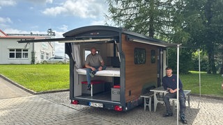 Die beiden Tüftler Nico und Nino König aus Engstingen (Kreis Reutlingen) sitzen vor und in einem ihrer Tiny Houses auf Rädern.