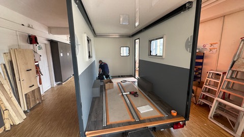 Ein Wohnanhänger wird in der Produktionshalle der Firma "TheCuber" in Engstingen (Kreis Reutlingen) von einem Handwerker aus Einzelteilen zusammengebaut.