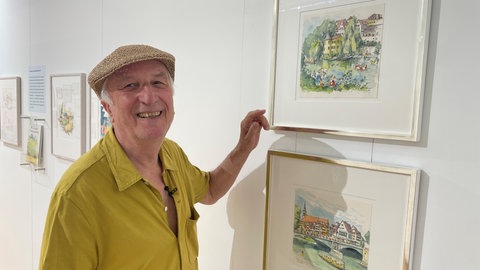 Peter Gaymann steht vor zwei seiner Bilder, Peter Gaymann Ausstellung im Neuen Kunstmuseum in Tübingen