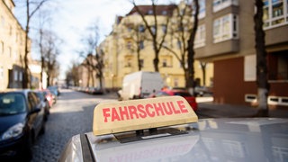 Symbolbild: Ein Auto mit einem "Fahrschule"-Schild fährt durch eine Straße. Ein Fahrlehrer aus dem Kreis Sigmaringen wurde wegen Vergewaltigung angeklagt.
