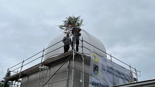 Mitarbeiter der Firma Rosenberger Bau haben beim Richtfest einen Baum am Gerüst gestellt.