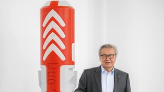 Klaus Fischer, Chef des Dübel- und Technikunternehmen Fischer in Waldachtal, steht neben dem übergroßen Modell eines Dübels. Klaus Fischer wird 75 Jahre alt.