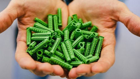 Eine Handvoll grüner Fischer-Dübel. Firmenchef Klaus Fischer aus Waldachtal wird 75 Jahre alt.