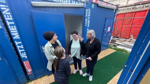 Container auf einer Baustelle in Bodelshausen. Mehrere Frauen unterhalten sich davor. Ihre Wohnungen werden bei laufendem Betrieb saniert.