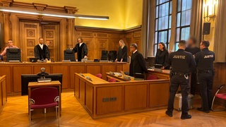 Beim Prozessauftakt im Tübinger Landgericht: Links im Bild sind Schöffen und Richter, rechts die Verteidigung, der Angeklagte und zwei Justizvollzugsbeamte. Der Angeklagte wird beschuldigt, einen Mann entführt und erpresst zu haben.