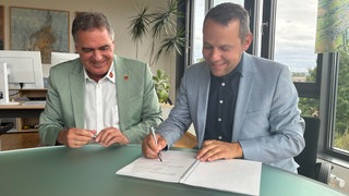 Die Stadtwerke Tübingen und der Dußlinger Bürgermeister Thomas Hösch unterzeichen den Kooperationsvertrag für den geplanten Windpark Rammert