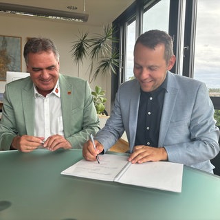 Die Stadtwerke Tübingen und der Dußlinger Bürgermeister Thomas Hösch unterzeichen den Kooperationsvertrag für den geplanten Windpark Rammert