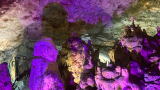 Bunt beleuchtete Felsen und Tropfsteine in der Bärenhöhle bei Sonnenbühl.
