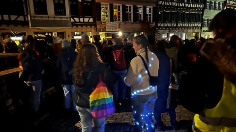 Demonstrierende mit Lichterketten und einem bunten Beutel in Regenbogenfarben bei der Demonstration gegen die Stadtbild-Aussagen von Kanzler Merz und OB Palmer.