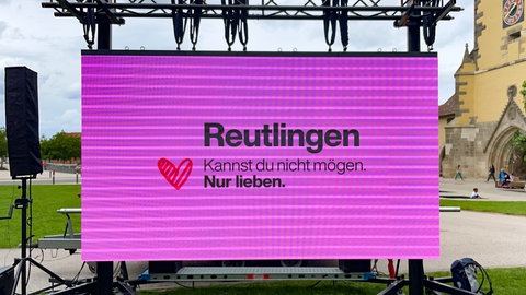Auf einer LED-Wand steht auf pink farbenem Untergrund der Werbespruch: "Reutlingen kannst du nicht mögen. Nur lieben."