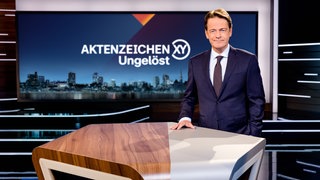 "Aktenzeichen XY... Ungelöst"-Moderator Rudi Cerne steht im Studio und lächelt in die Kamera. In der Sendung am 5.11.25 wird auch der rätselhafte Fall der mutmaßlichen Entführung auf einem Tübinger Supermarkt-Parkplatz behandelt.