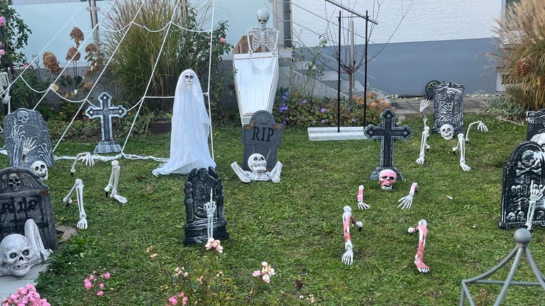 Skelette, die aus dem Gras im Vorgarten zu kriechen scheinen, Grabsteine, ein Spinnenetz. An Halloween wird dieses Haus gruselig dekoriert. 