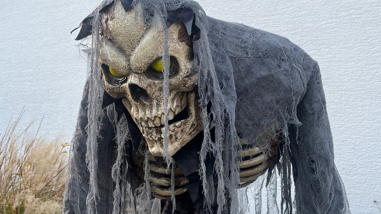 Ein Skelett mit gelben Augen steht vor einem Haus. Mehrere Häuser in Reutlingen-Degerschlacht sind an Halloween gruselig geschmückt.