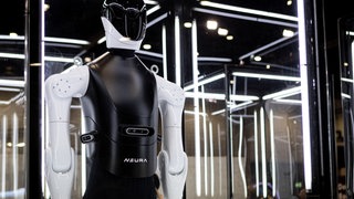 Ein schwarzer Roboter mit Visir und weißen Gliederarmen hinter einer Vitrine. Der Metzinger Roboterhersteller Neura Robotics hat sich einen Großauftrag von mehr als 300 Millionen Euro gesichert. Auftraggeber ist der bayerische Autozulieferer Schaeffler.