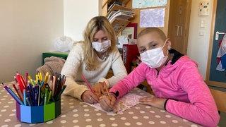 Die Tübinger Medizinstudentin Laura ist "MEDI Patin" und sitzt mit der krebskranken Florina an einem Tisch und malt.