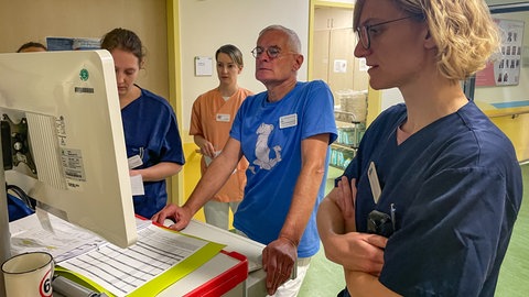 Arzt steht zusammen mit weiteren Ärzten und Pflegepersonal bei einer Besprechung an einem Computer Terminal. Frühchenstation Reutlinger Klinikum am Steinenberg.